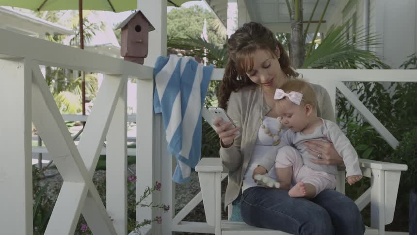A woman holds a baby on a porch