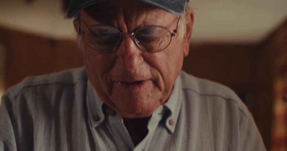 Elderly man sitting interacting with an electronic device