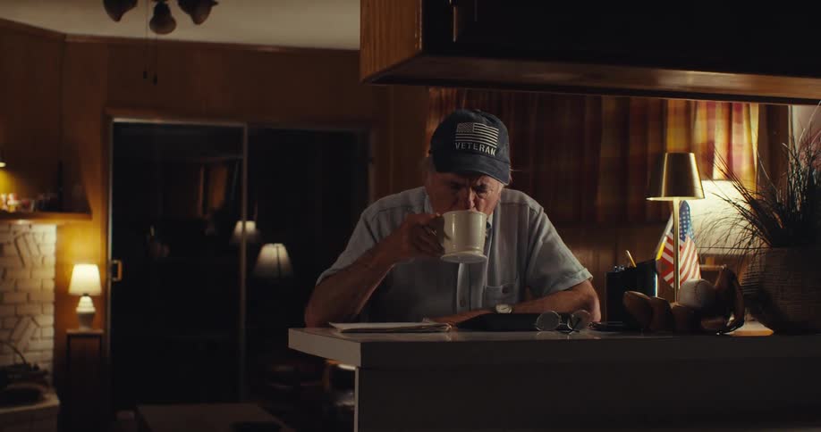 A man is drinking coffee from a mug in his house