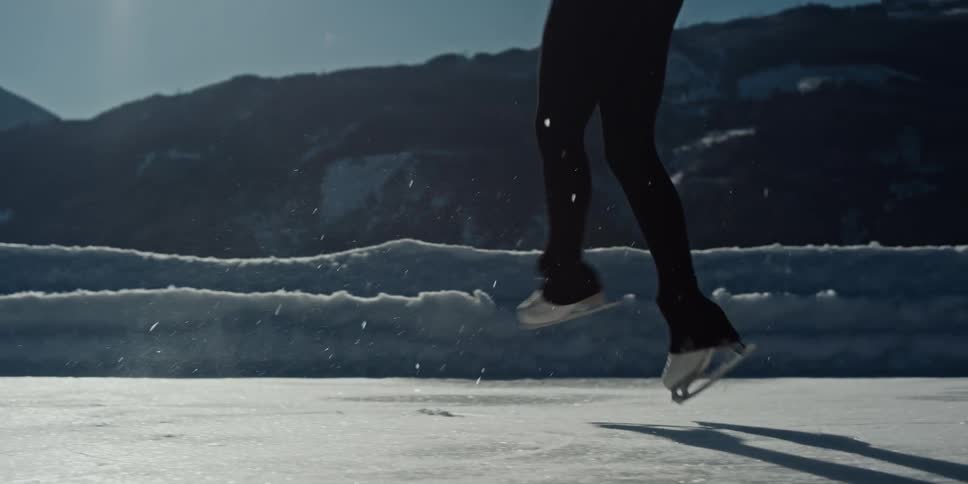 A man wearing skates does a spinning jump on the ice