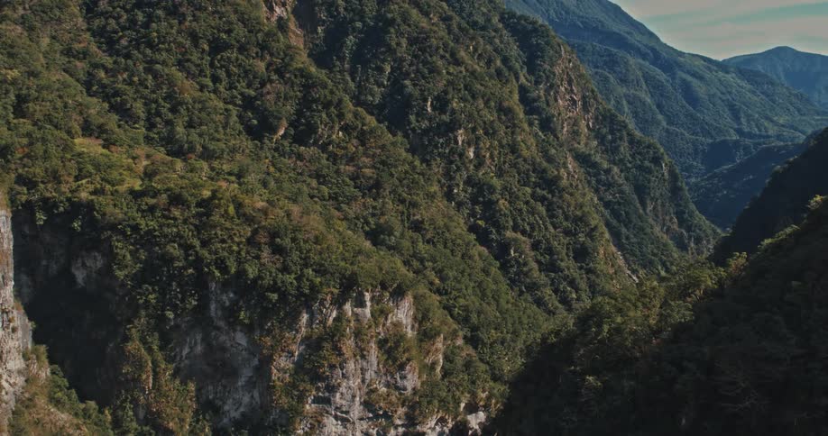 Steep slopes covered with dense vegetation form a deep gorge between the mountains