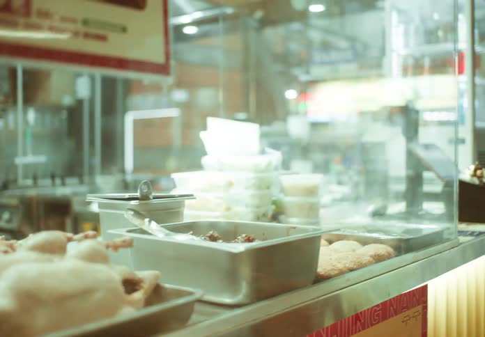 Restaurant counter with display case displays platters of oriental food