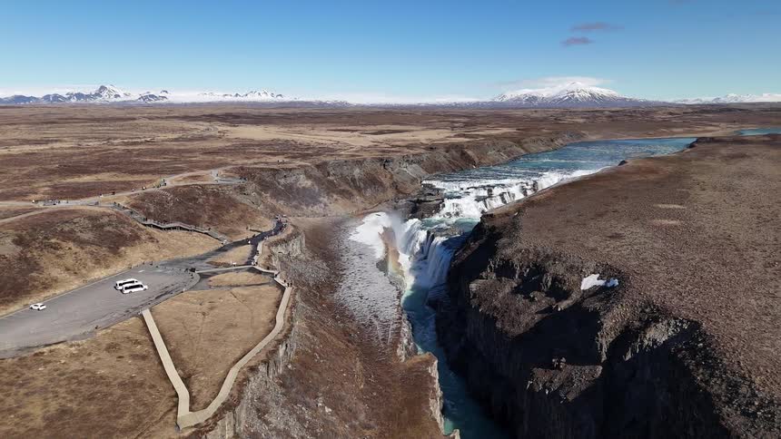 A wide river cuts through the barren landscape ending in a waterfall