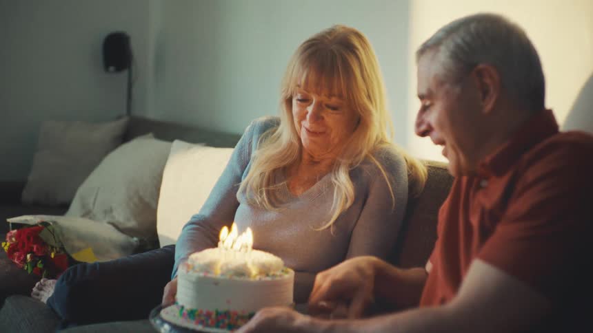Couple smiles together while celebrating a birthday with a birthday cake