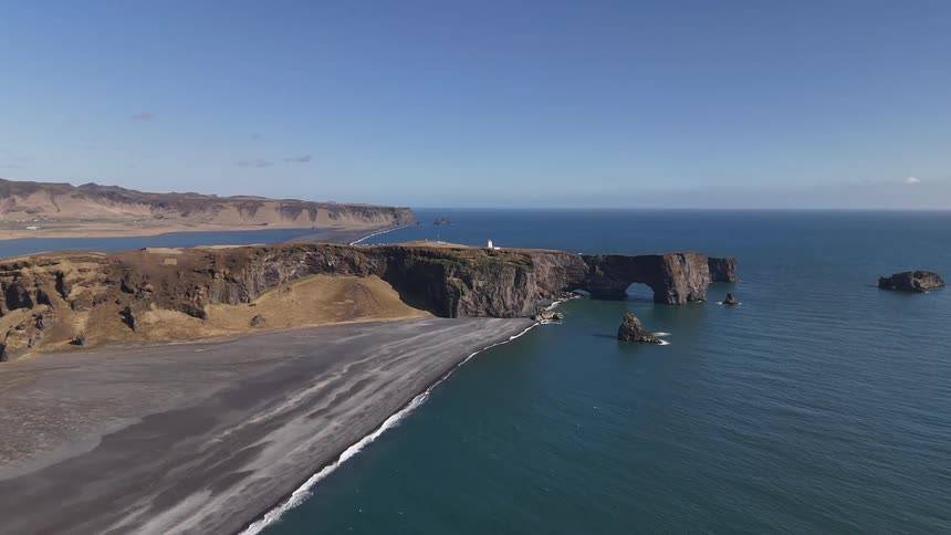 Small waves roll onto a beach that has cliffs