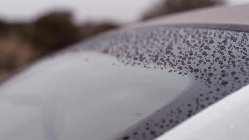 Windshield wipers are moving across the windshield of a car