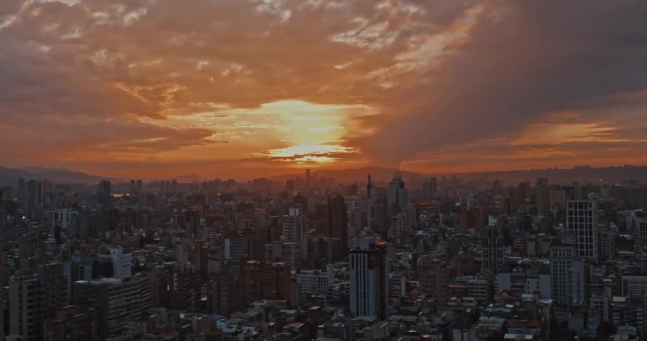 The sun casts vibrant rays over a city as it sets