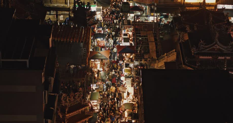 A large crowd walks on the streets of a city late at night