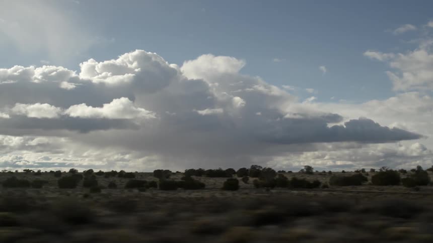 Clouds hang above a flat desert landscape