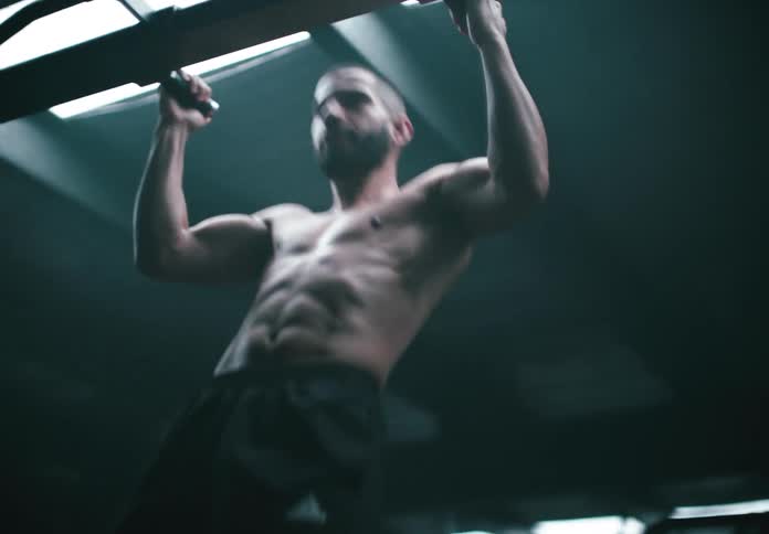 Man doing pull ups in the gym stops and jumps down