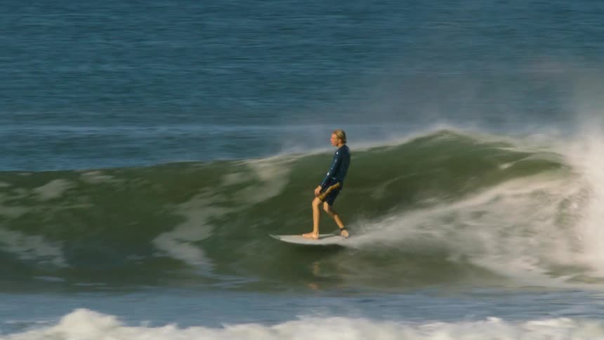 A man is surfing fast on the wave
