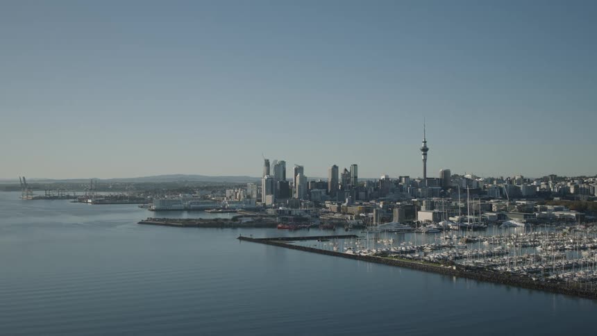 A large city with tall buildings and a dock on the coast with several boats anchored