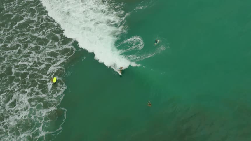 A surfer performs a sharp turn on a wave in the ocean while others wait nearby in the water