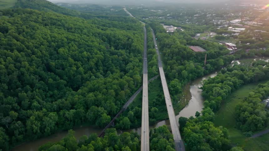 A long bridge over a river and a highway crossing through a forest