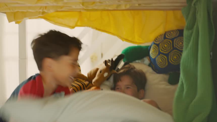 Two children playing in a room surrounded by stuffed toys