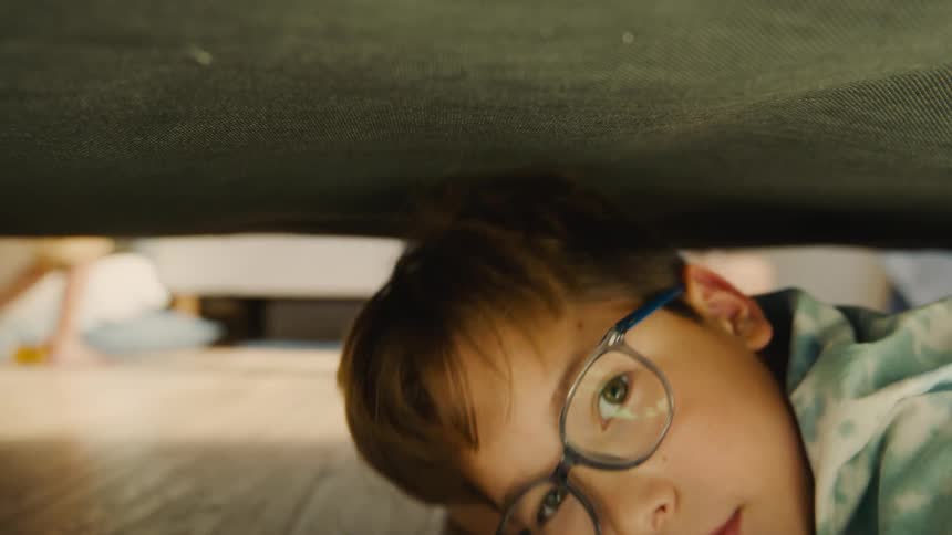 Two children playing under a bed