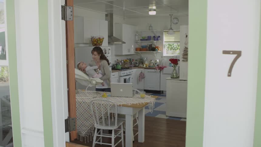 A woman holds a baby in a kitchen