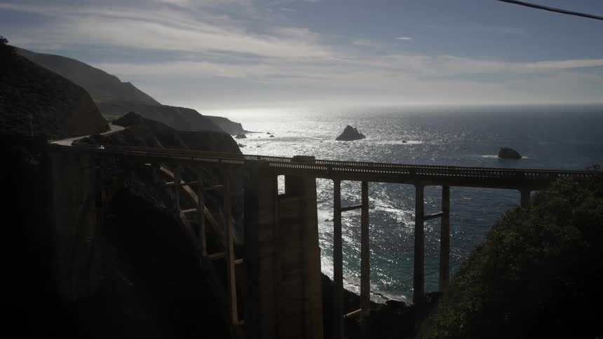 A large bridge gaps a mountain by the shore