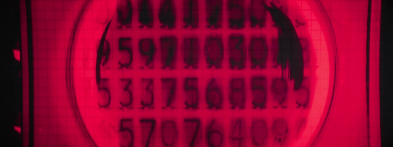 A glowing red circular display shows a grid of dark stylized changing digits within a larger rectangular frame
