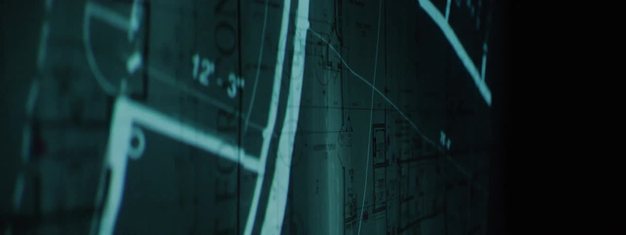 A projection is superimposed over the blueprints in the dark