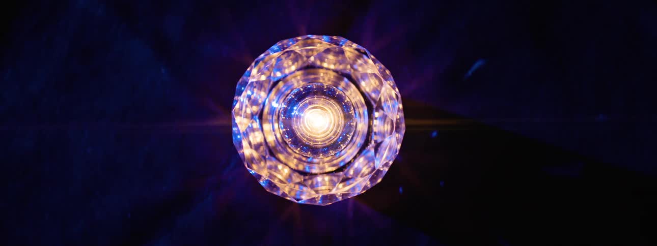 A chandelier on the ceiling spinning 360 degrees illuminating warm light mixed with red and blue tones