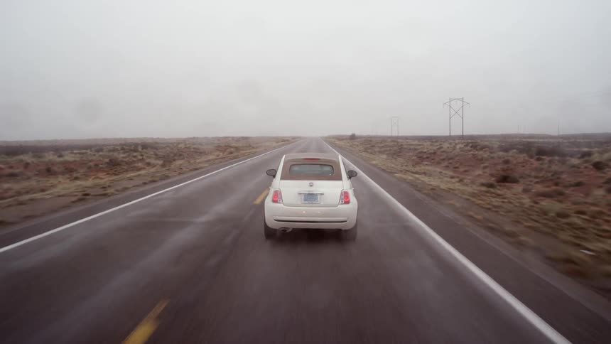 A car drives down a desert road