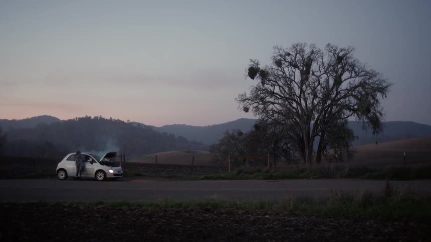 A person walks around a broken down car