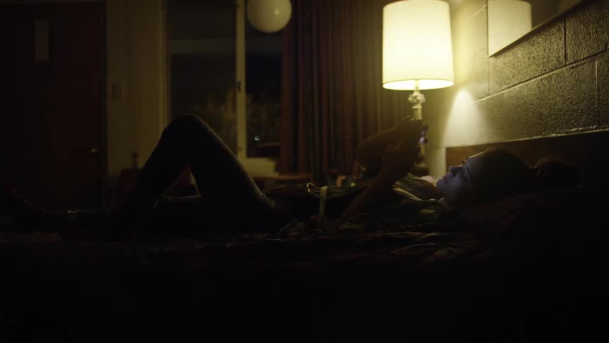 A woman lays in bed browsing on her phone