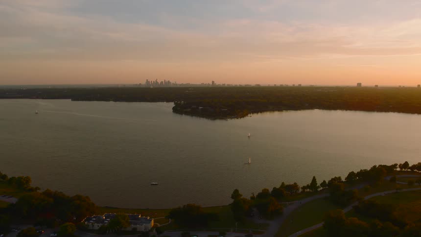 An aerial shot of a large lake at sunset with a distant city skyline on the horizon