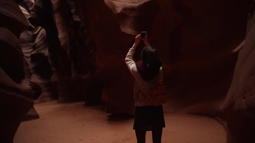 A woman feels around a cavern as she walks through