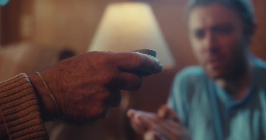 Man sitting talking to another person who is holding a remote control