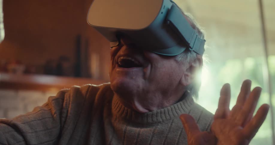 A man is smiling while waving a controller using a vr headset