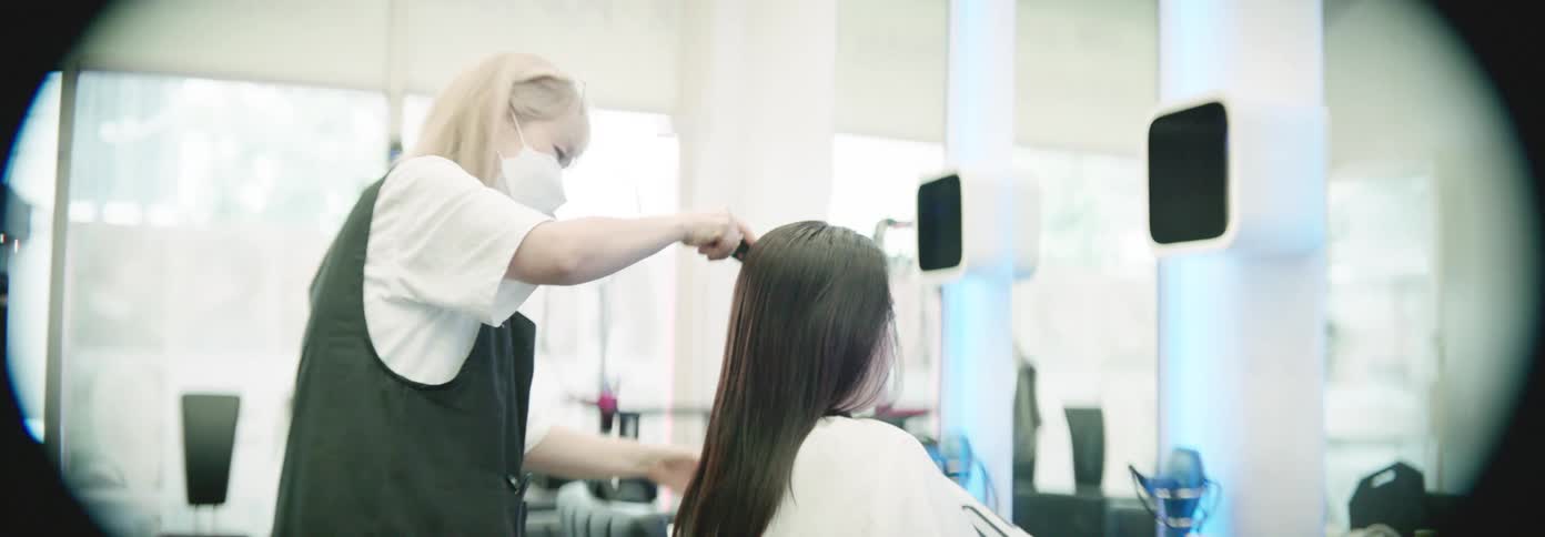 A barber is cutting a womans hair in the barbershop