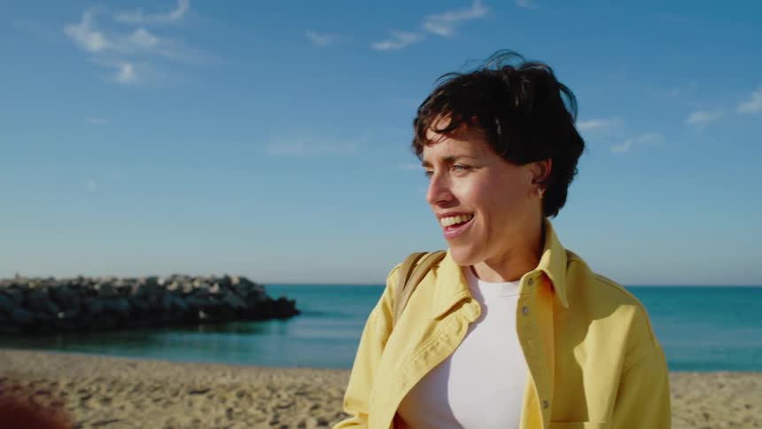 Two women walking in the sand on a beach with beautiful turqoise water on a sunny day as they chat and catch up on life.