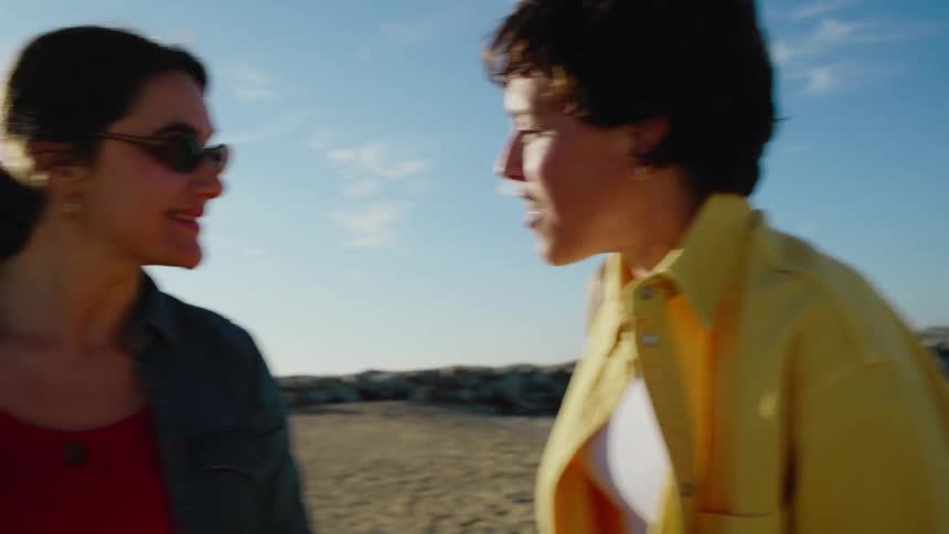 Two girlfriends on the beach talking happily