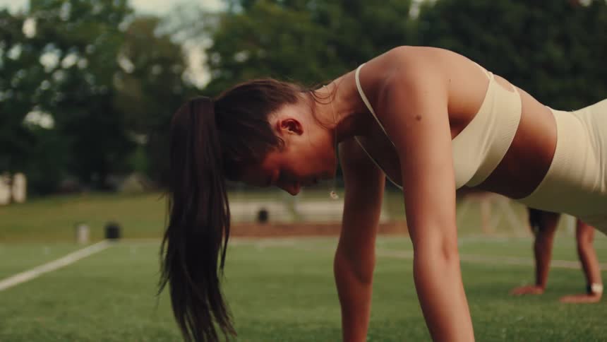A woman is exercising outdoors in a plank position during a workout session