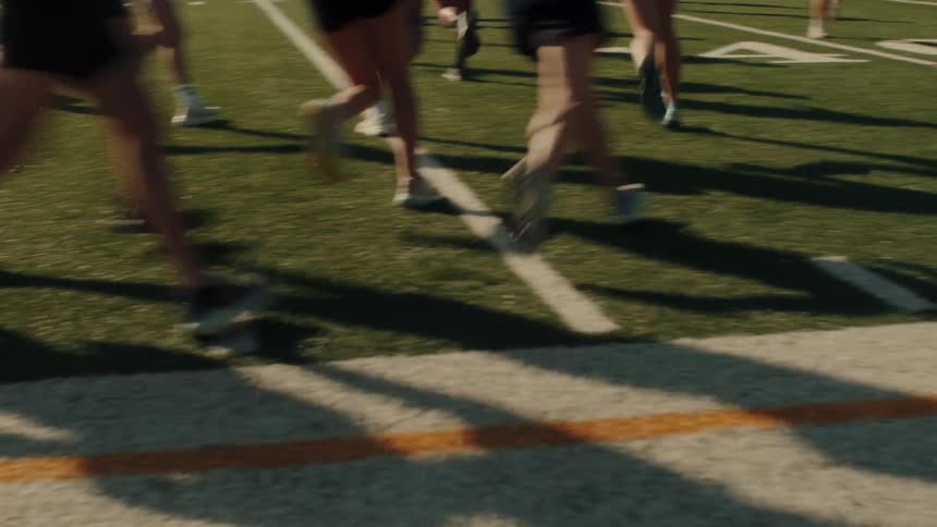 A group of people jog in laps in a field during the day