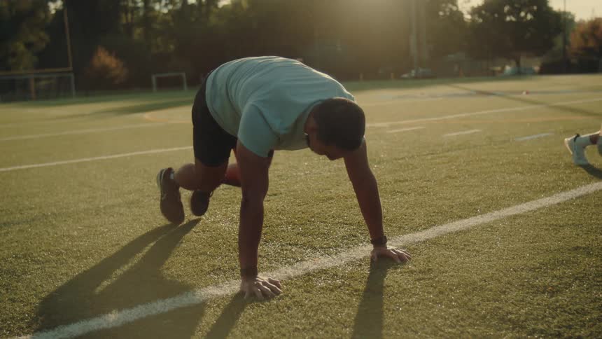 A man exercises on a field in daytime