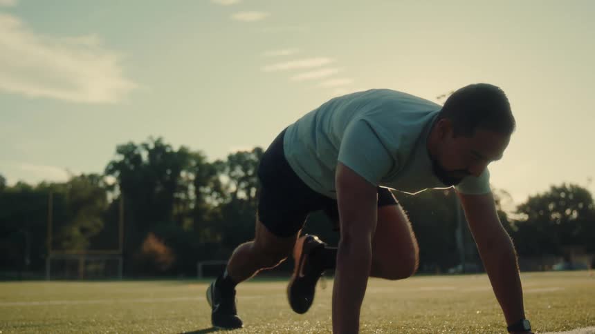 Man exercises alone on a football field on a cloudy day