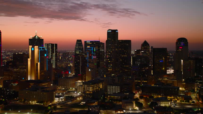 Aerial night view of a vibrant city glowing with building lights and moving vehicle trails