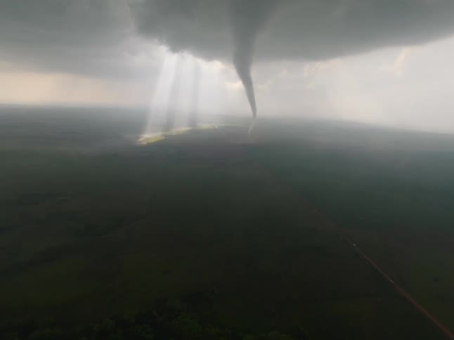 A tornado storm in a grassland at midday causing dark clouds to cover the sky