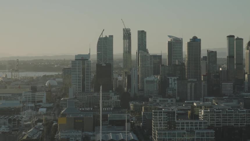 Wide aerial shot of a modern city skyline at dawn with highrise buildings and construction cranes