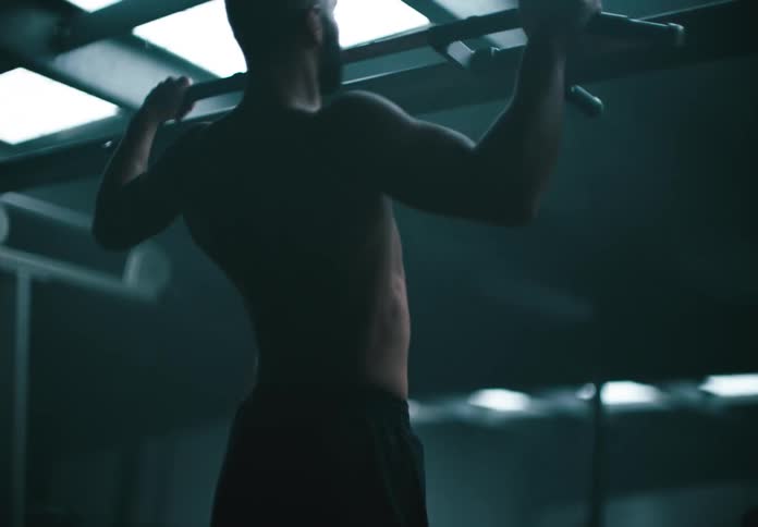A man is doing pull ups it the gyms