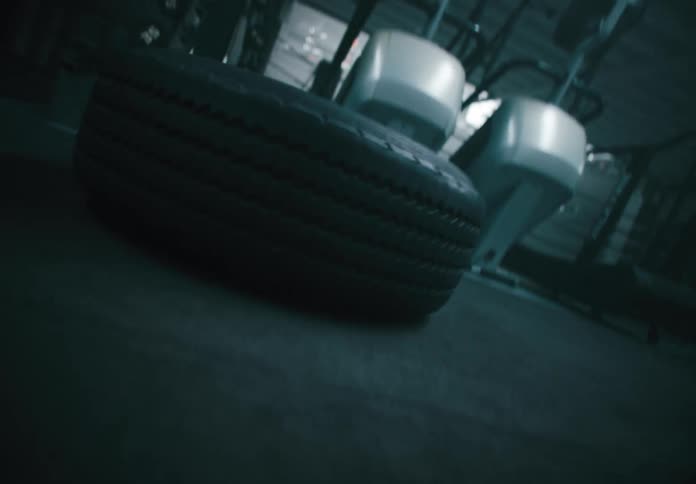 A person is performing an intense workout flipping a large tire in a gym setting