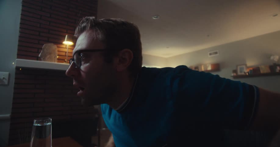 A worried man leans toward his computer screen visibly upset while watching market data