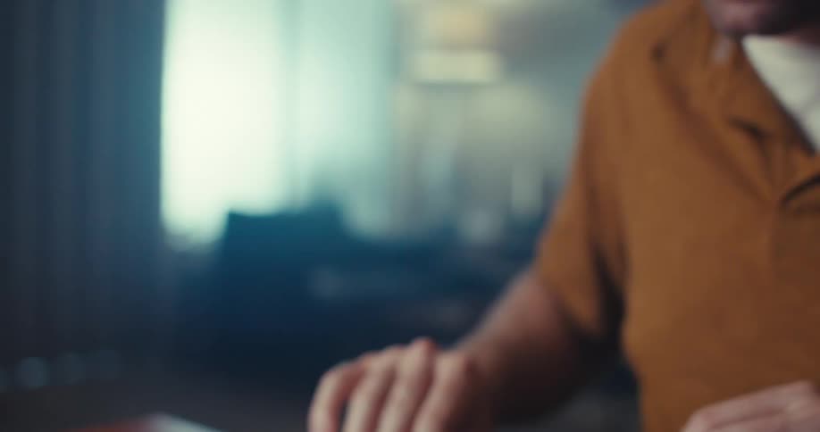 A man wearing glasses building a house of cards in his living room