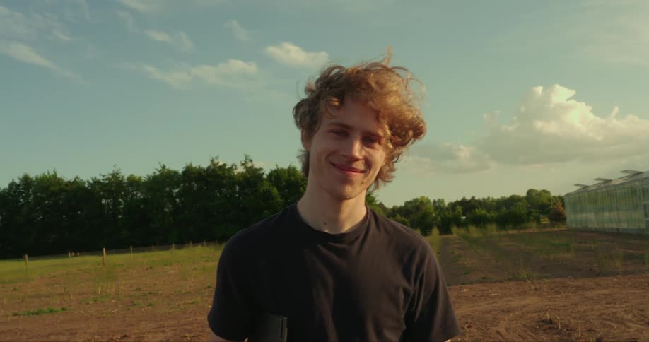 A handsome young man smiles directly at the camera while posing confidently