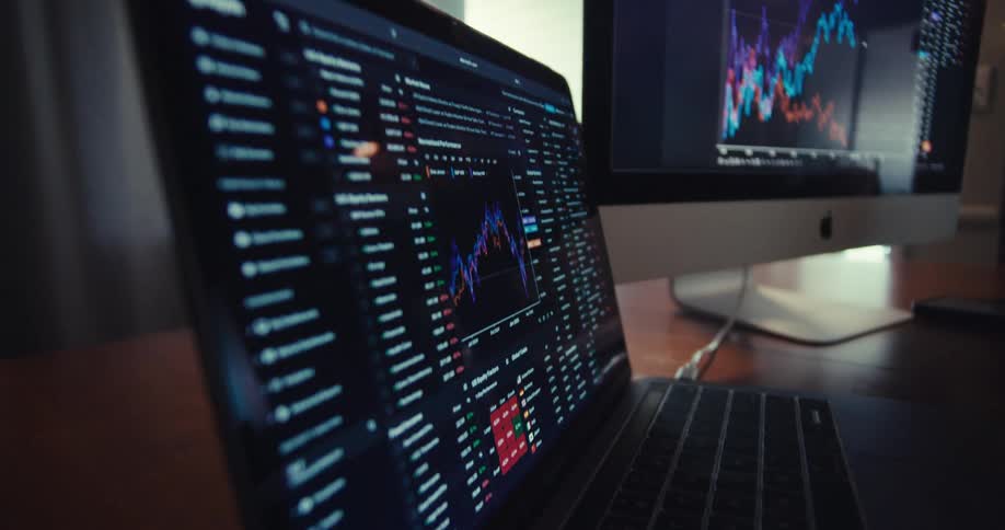 Closeup shot of multiple screens displaying realtime stock market data and charts
