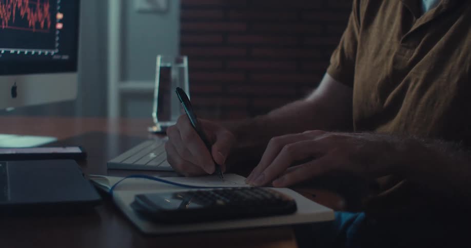 A man writes something down in a notebook