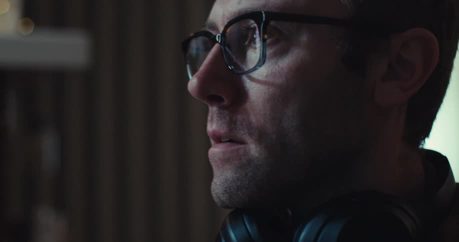 Close up of a mans face as he smiles while looking at a screen
